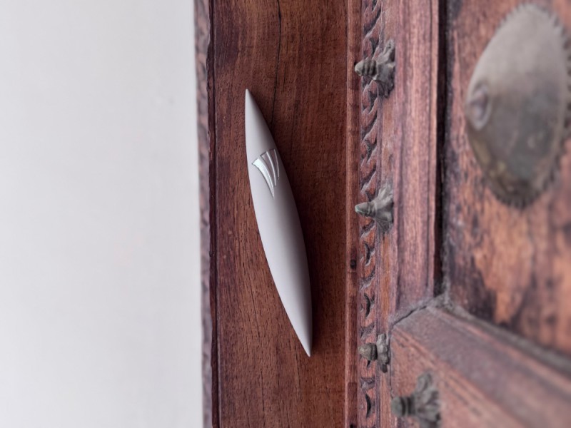 Large grey Apollo mezuzah installed on wooden door frame