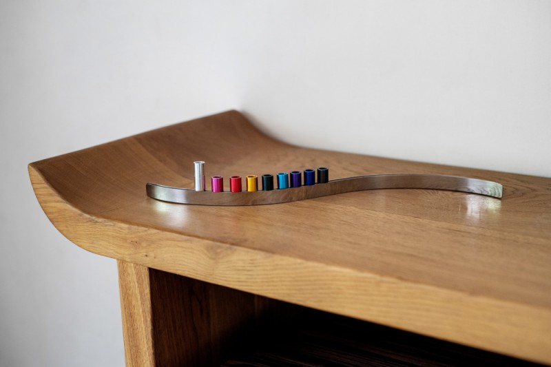 Modern slide magnet menorah displayed on wooden table with colorful anodized candle holders